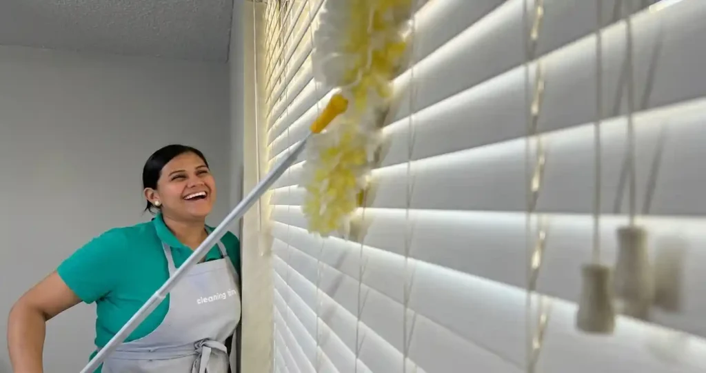 House cleaner dusting window blinds in a residential home in Austin