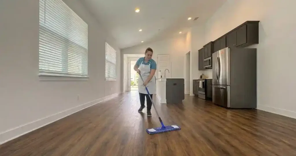 House cleaner mopping hardwood floors in an open living room and kitchen in Austin