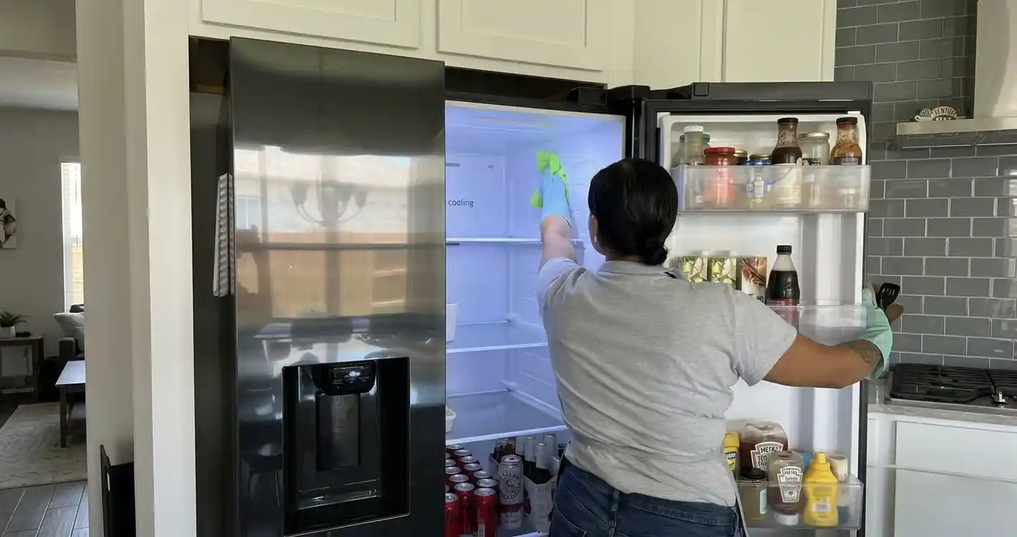 House cleaner wiping inside refrigerator in a residential kitchen in Round Rock