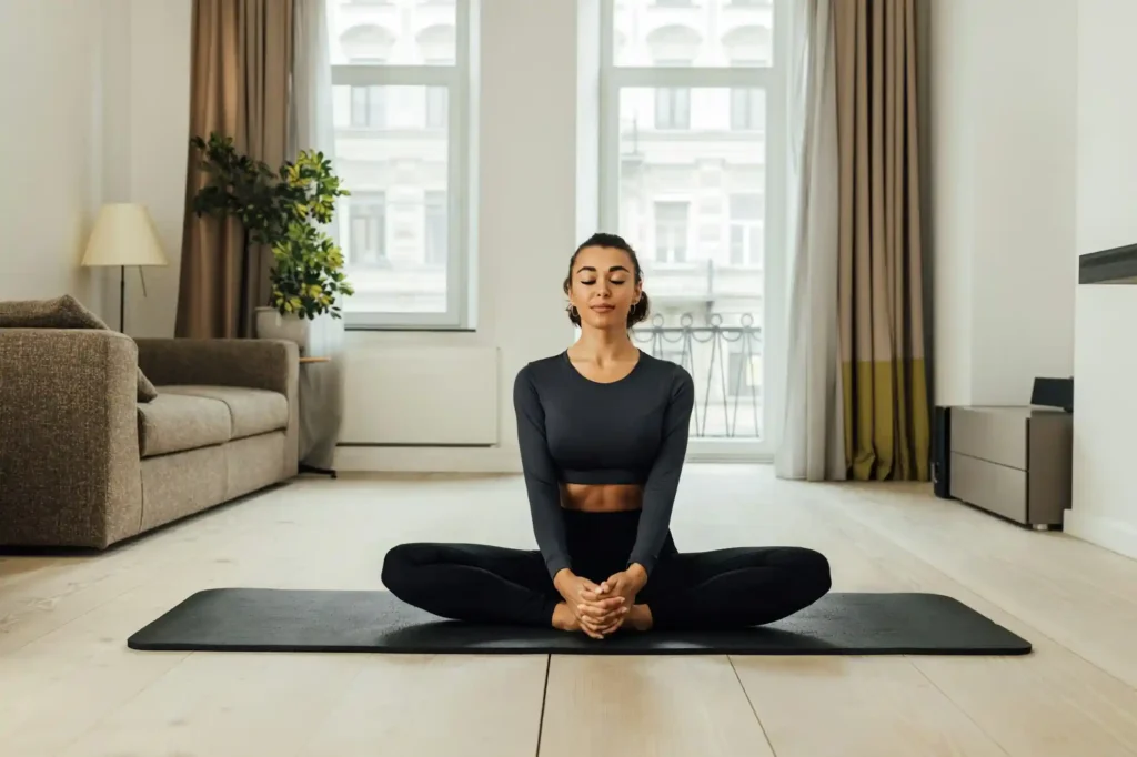 Woman meditating on a yoga mat in a clean living room in Austin