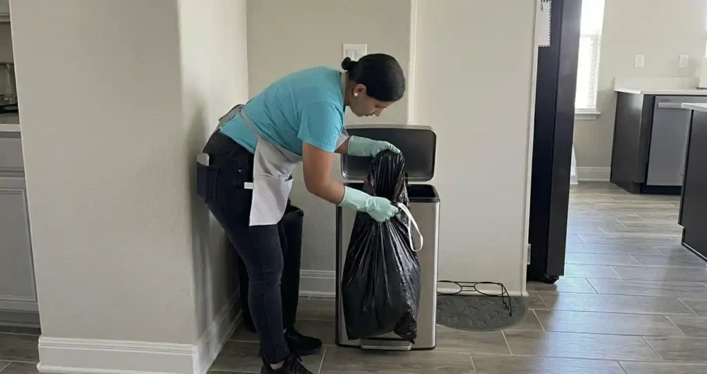 House cleaner removing a trash bag from a kitchen trash can in a residential home in Austin