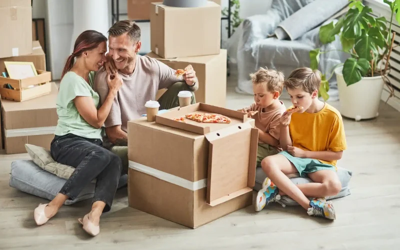 Family eating pizza among moving boxes in a clean new home in Austin